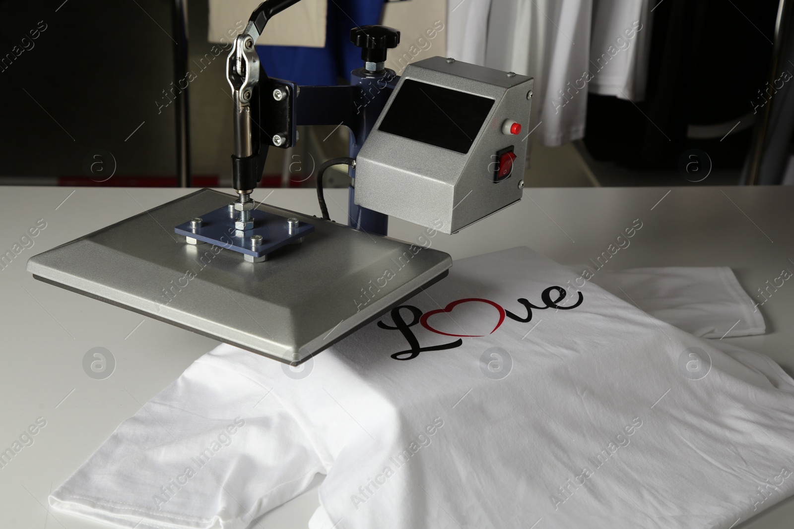 Photo of Printing logo. Heat press with t-shirt on white table