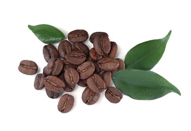 Pile of roasted coffee beans with fresh leaves on white background, top view