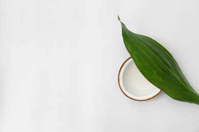 Photo of Half of fresh coconut and palm leaf on white background, top view