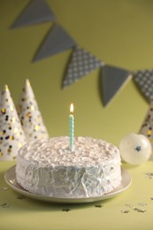 Photo of Tasty cake with burning candle on green background