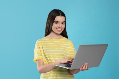 Photo of Teenage girl with laptop on light blue background. Space for text