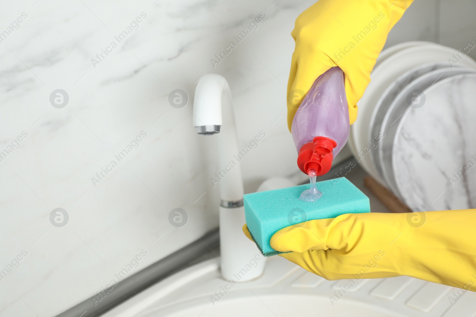 Photo of Person pouring cleaning product for dish washing onto sponge near kitchen sink. Space for text