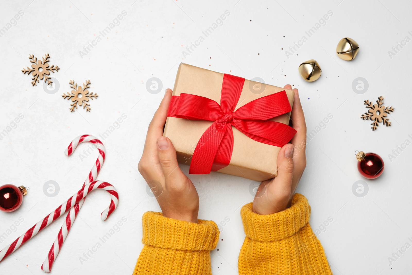 Photo of Young woman holding Christmas gift on white background, flat lay