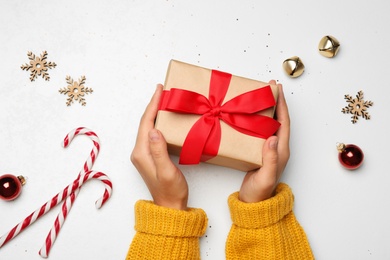 Photo of Young woman holding Christmas gift on white background, flat lay