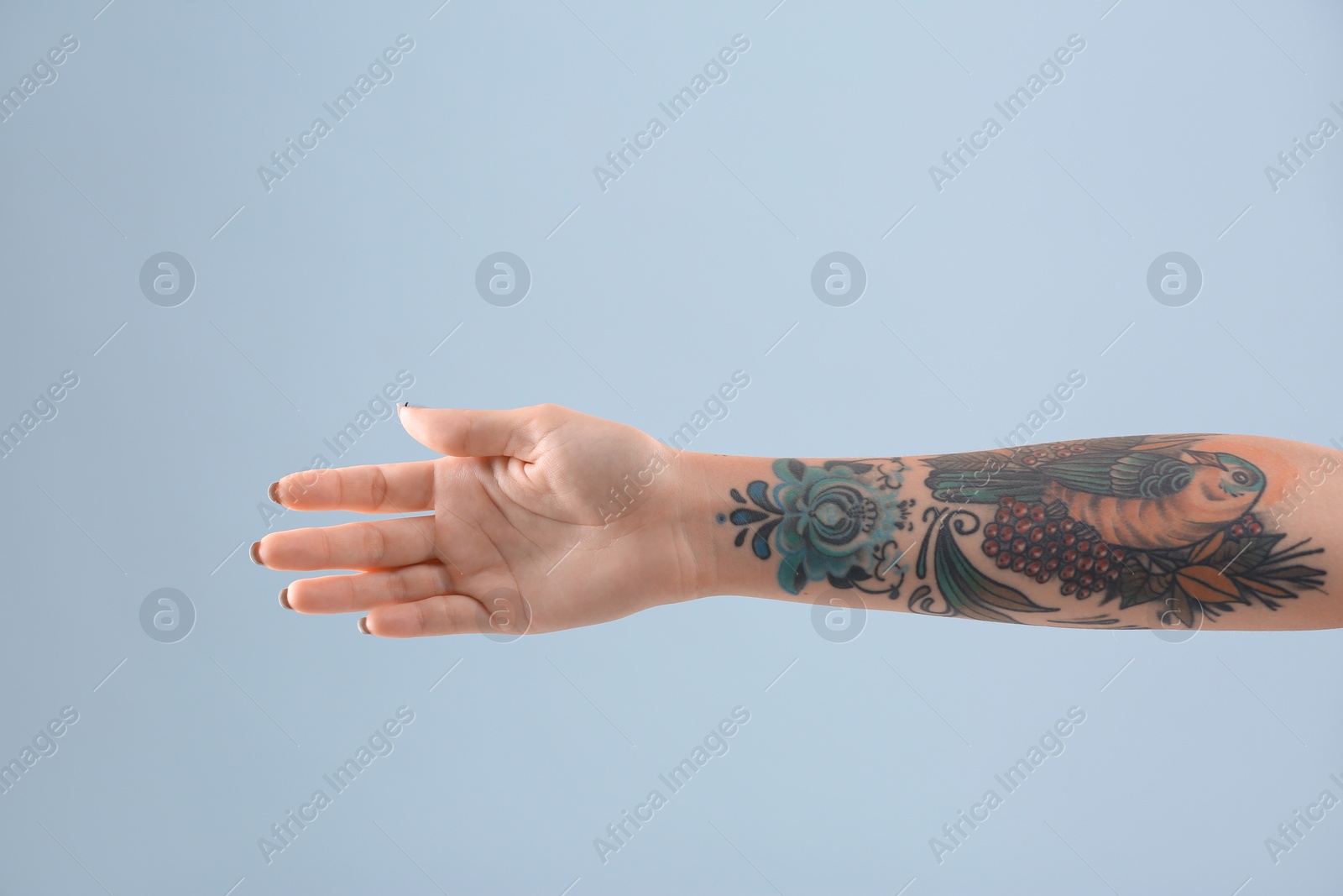 Photo of Female arm with tattoo on color background