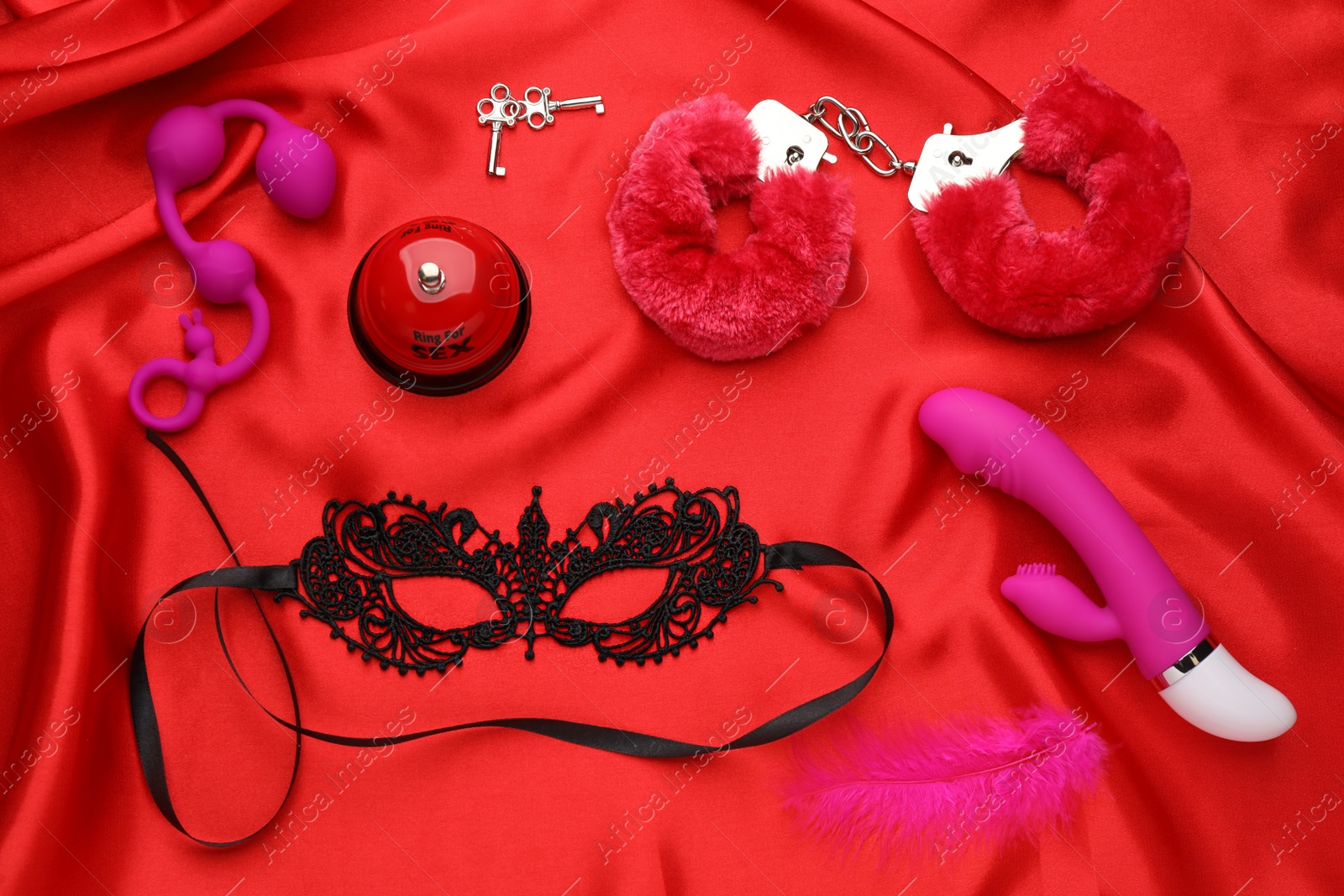 Photo of Sex toys and accessories on red fabric, flat lay