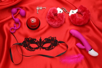 Sex toys and accessories on red fabric, flat lay
