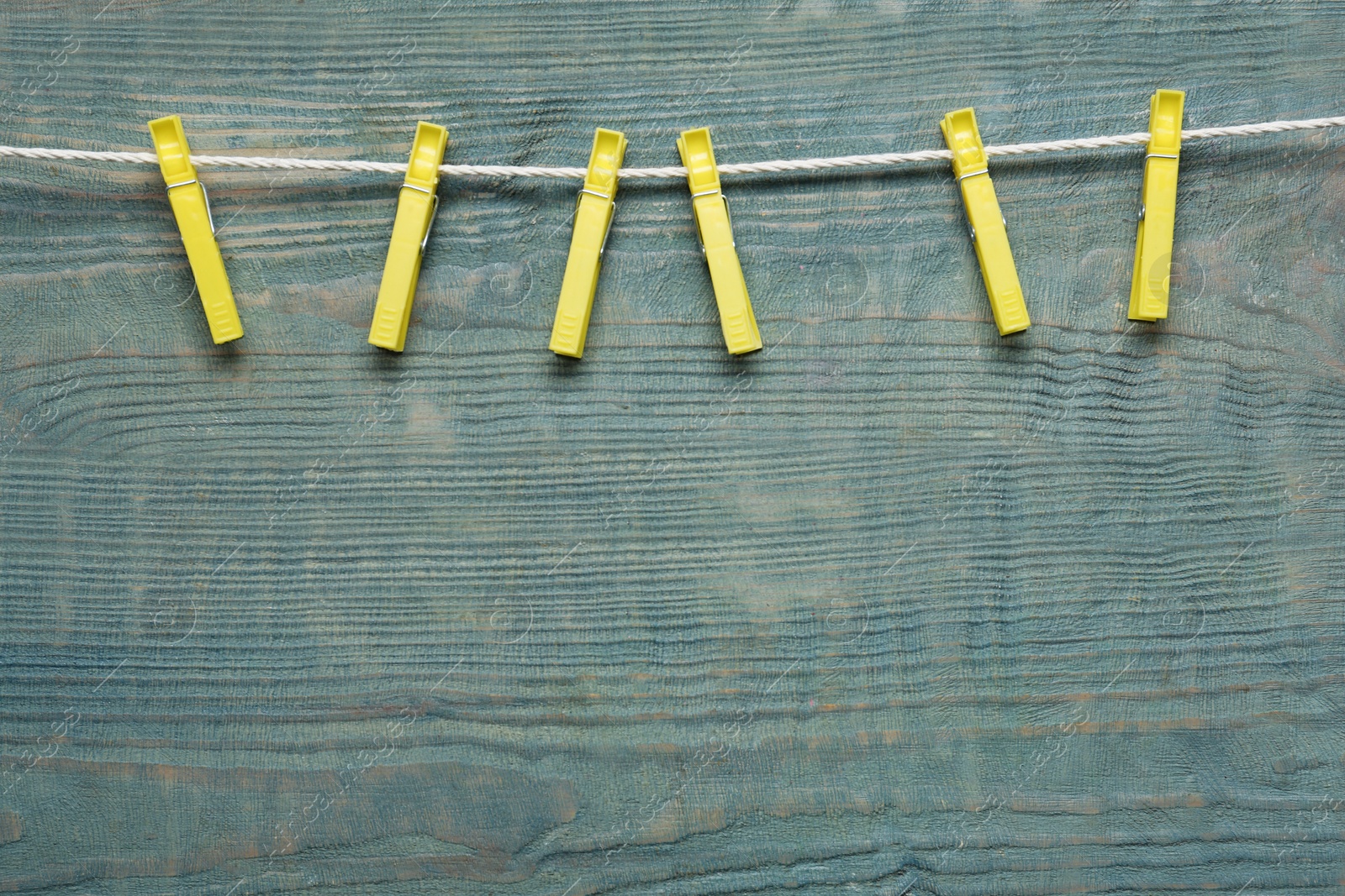 Photo of Plastic clothespins and rope on wooden background. Space for text