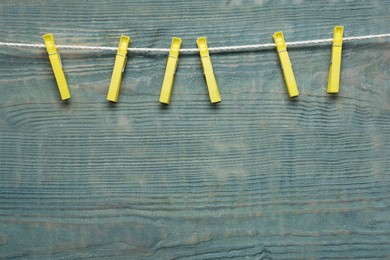 Photo of Plastic clothespins and rope on wooden background. Space for text