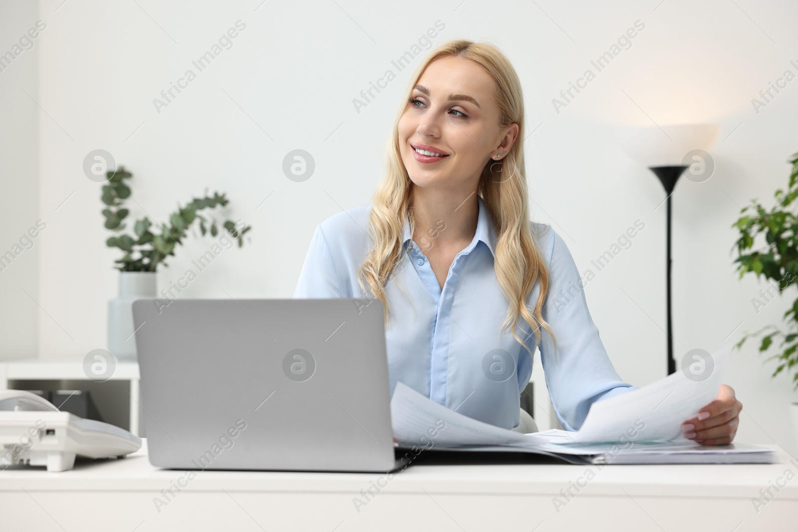 Photo of Happy secretary working with documents at table in office