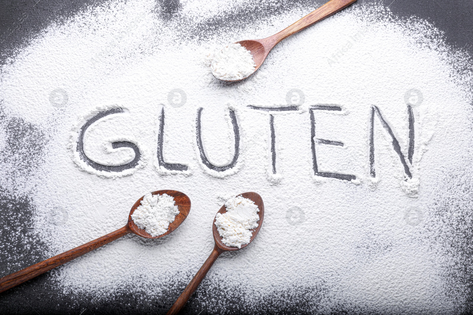 Photo of Word Gluten made with flour and wooden spoons on grey background, flat lay