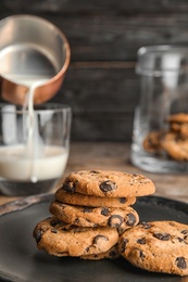 Photo of Plate with tasty chocolate chip cookies on wooden table