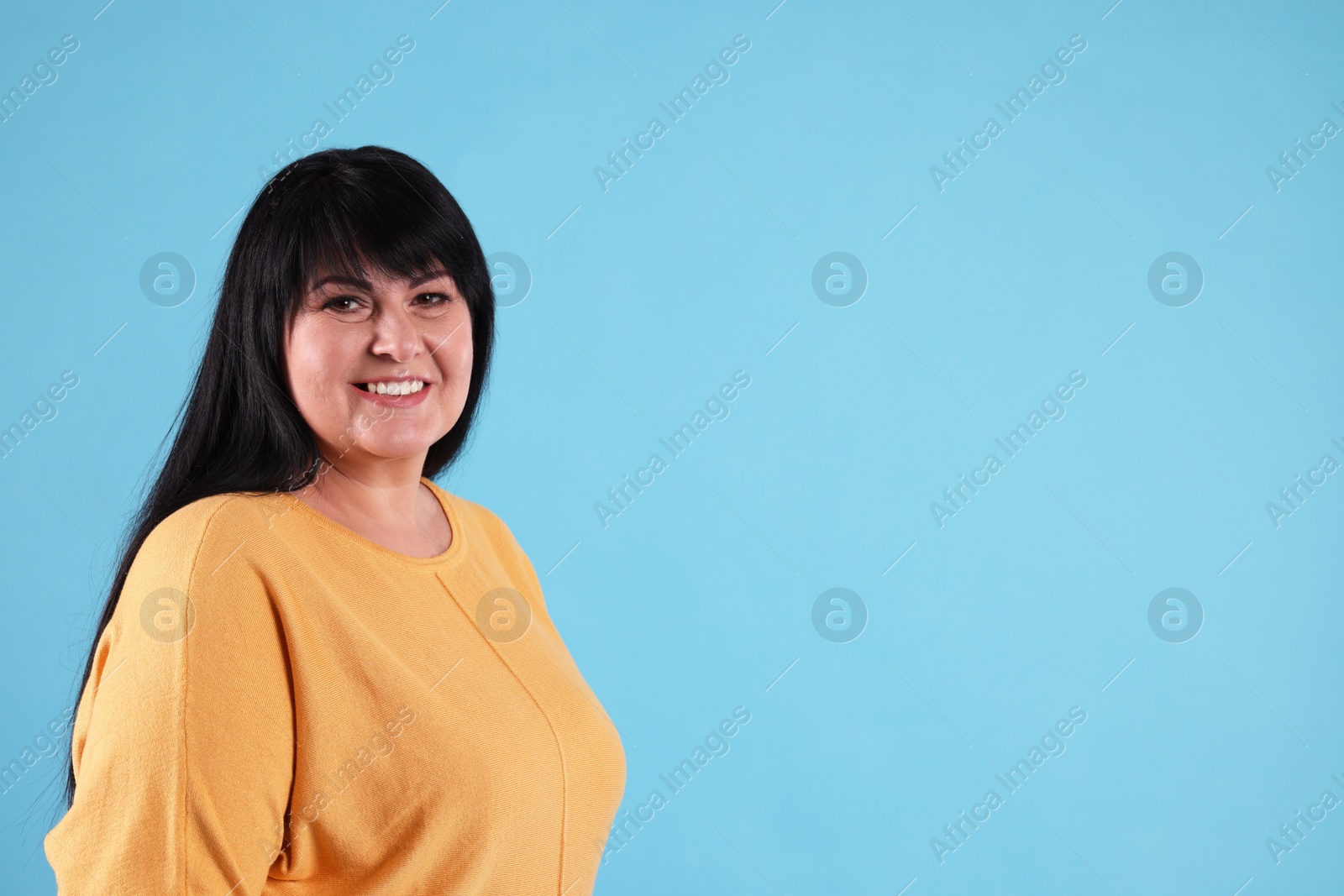 Photo of Beautiful overweight mature woman with charming smile on turquoise background. Space for text