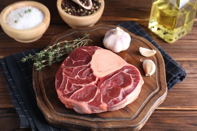 Photo of Piece of raw beef meat, garlic and thyme on wooden table, closeup