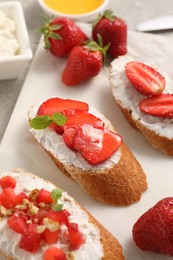 Delicious ricotta bruschettas with strawberry and mint on grey table