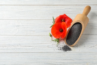 Scoop of poppy seeds and flowers on white wooden table, flat lay with space for text