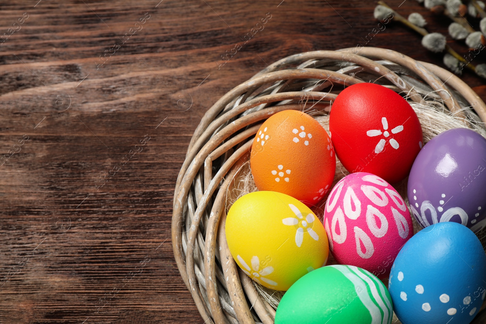 Photo of Colorful Easter eggs in decorative nest on wooden background, closeup. Space for text