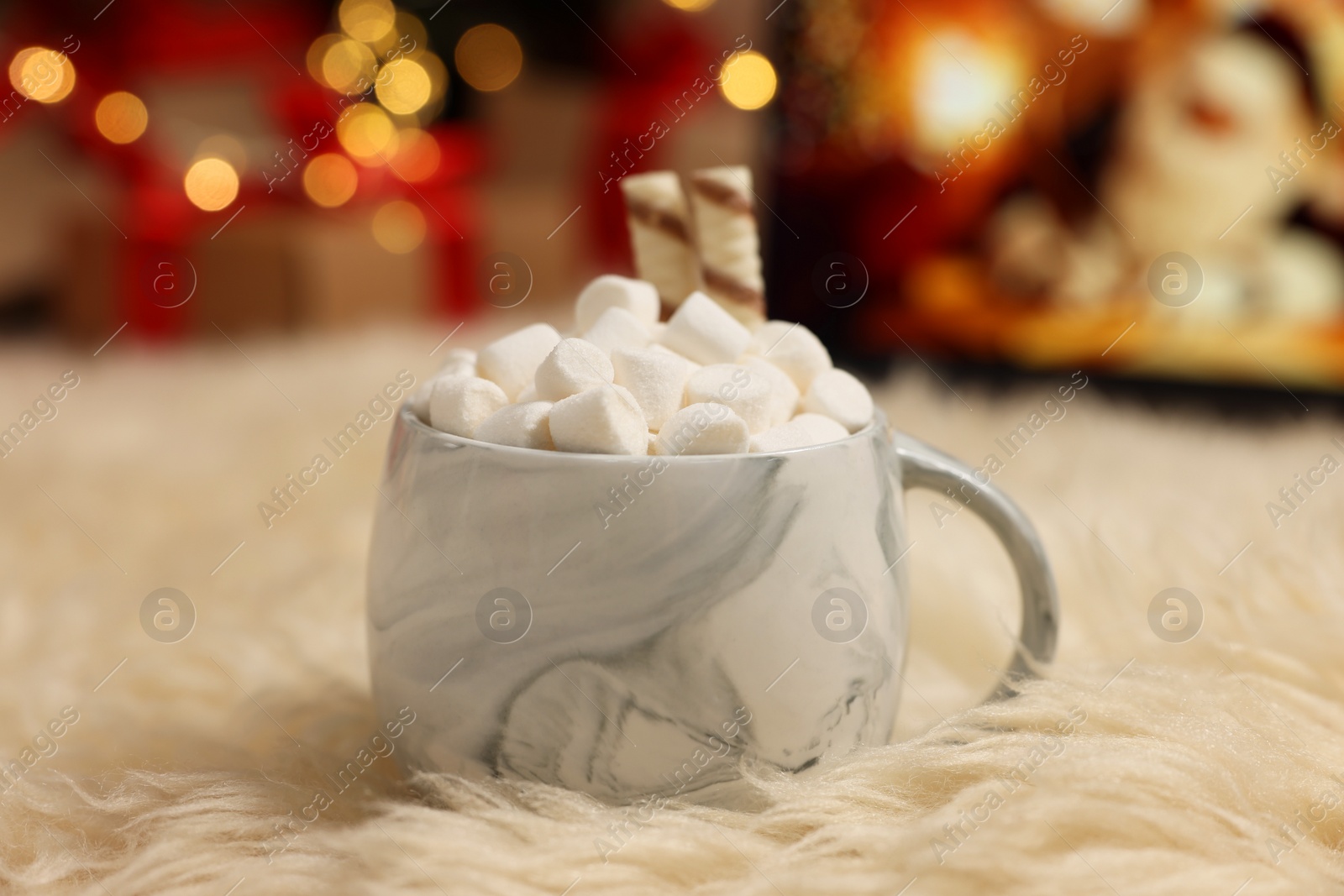 Photo of Christmas cocoa with marshmallows and wafer sticks in cup on soft carpet indoors, closeup