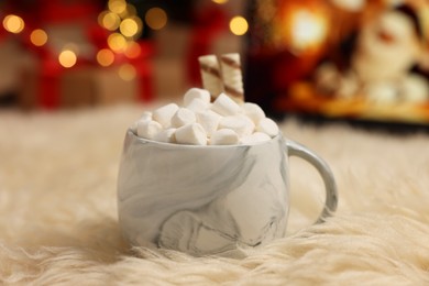 Photo of Christmas cocoa with marshmallows and wafer sticks in cup on soft carpet indoors, closeup