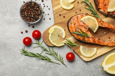 Photo of Tasty grilled salmon steaks and different ingredients on light grey table, flat lay. Space for text
