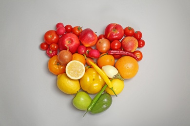 Heart made of ripe fruits and vegetables in rainbow colors on grey background, top view