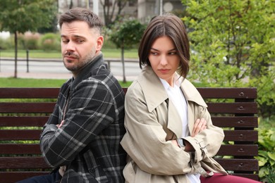 Photo of Unhappy couple sitting on bench outdoors. Relationship problems