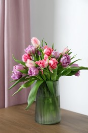 Photo of Beautiful bouquet of colorful tulip flowers on wooden table indoors