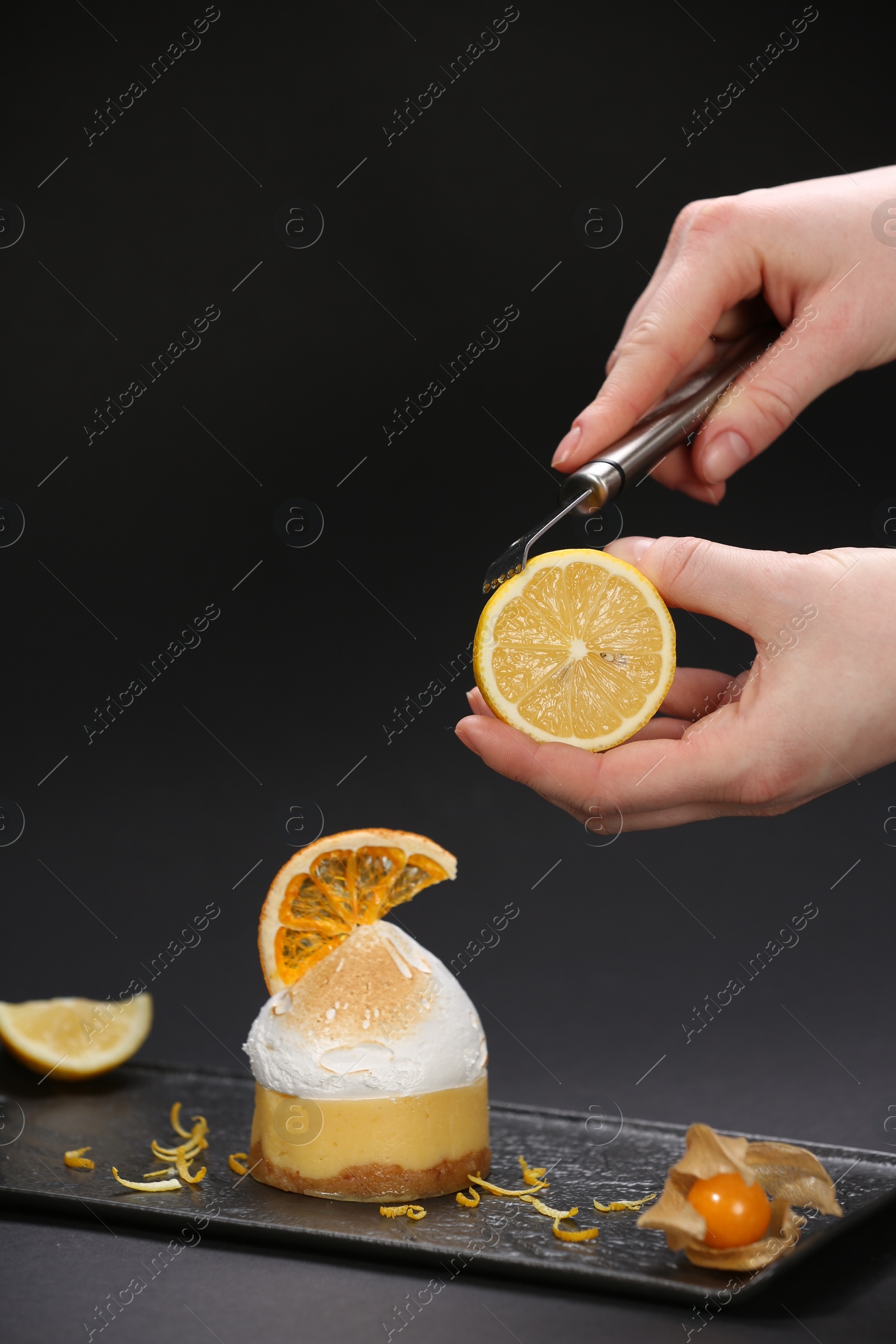 Photo of Food stylist creating beautiful composition with delicious dessert on black background, closeup