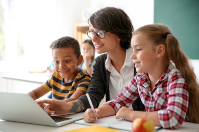 Photo of Female teacher helping children with assignment at school