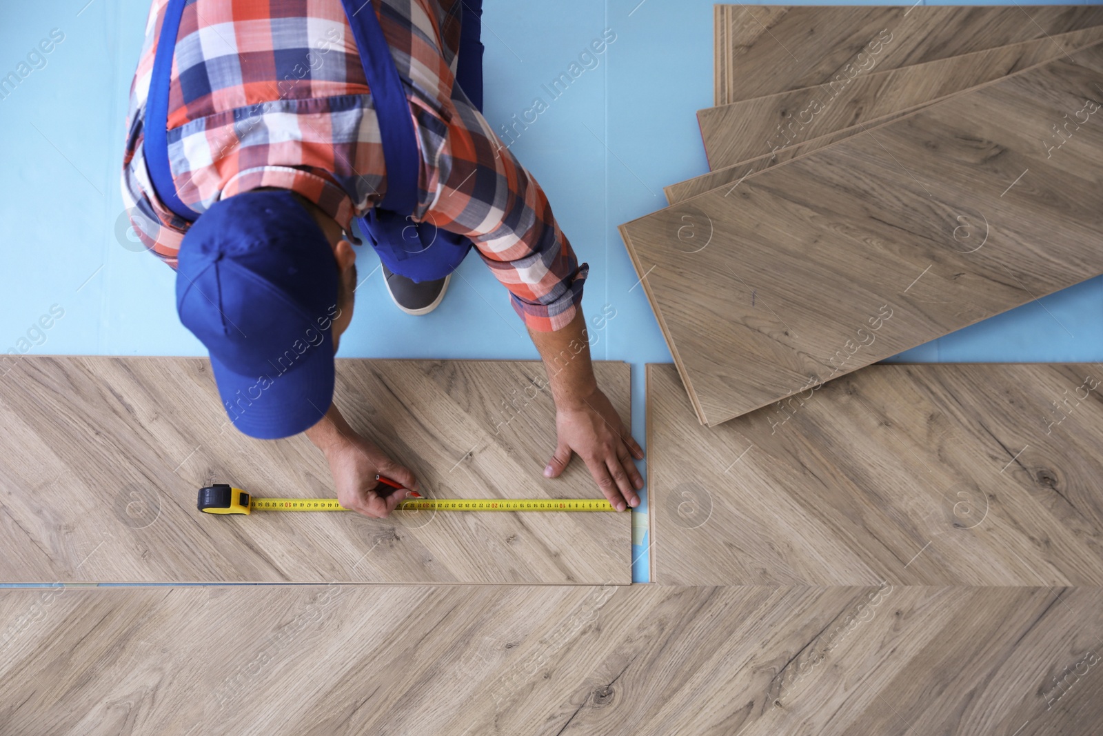 Photo of Worker installing laminated wooden floor indoors, above view