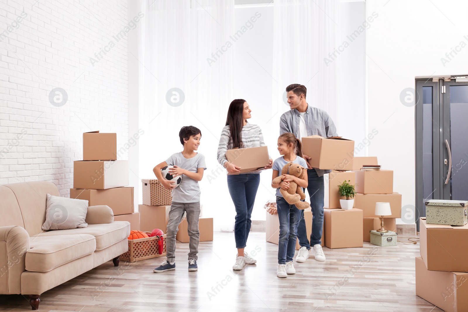 Photo of Happy family in room with cardboard boxes on moving day