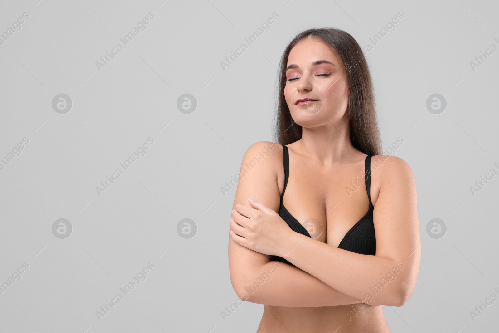 Photo of Portrait of young woman with beautiful breast on light grey background. Space for text