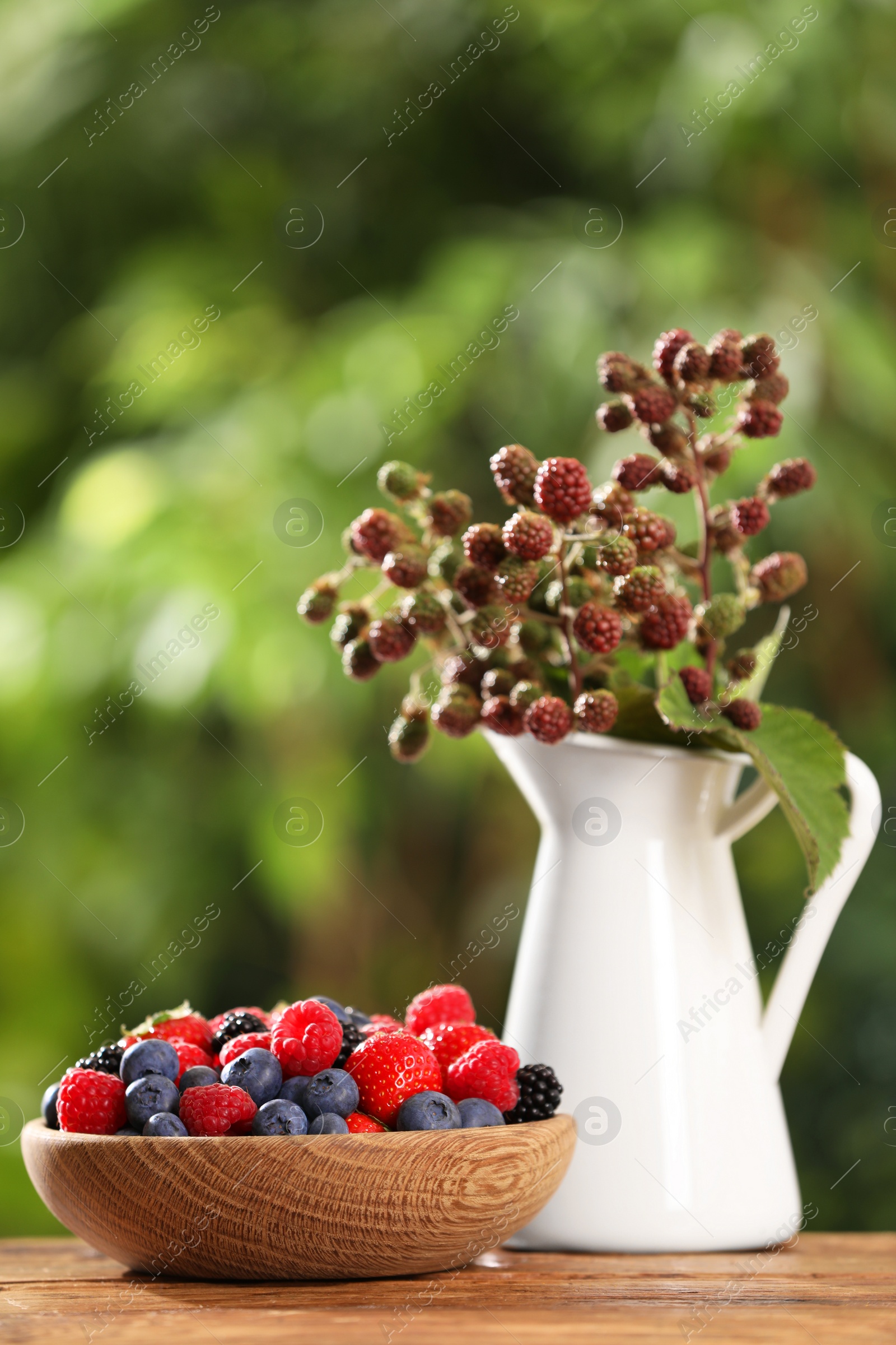 Photo of Different fresh berries on wooden table outdoors