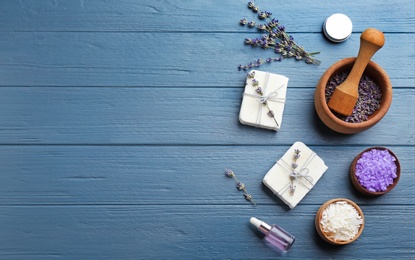 Photo of Flat lay composition of handmade soap bars with lavender flowers and ingredients on blue wooden background. Space for text