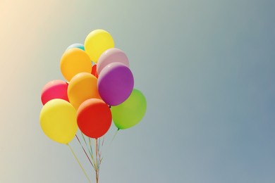 Image of Colorful balloons flying in blue sky on sunny day. Space for text