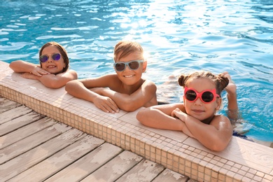 Happy children with sunglasses in swimming pool on sunny day