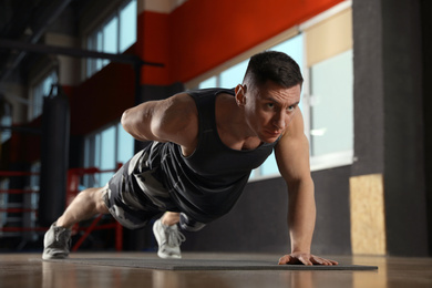 Photo of Man doing plank exercise in modern gym