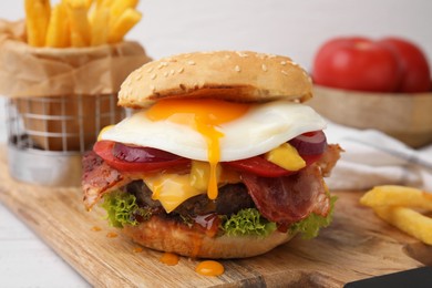 Photo of Delicious burger with fried egg on white wooden table, closeup