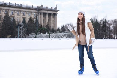 Image of Happy woman skating along ice rink outdoors. Space for text