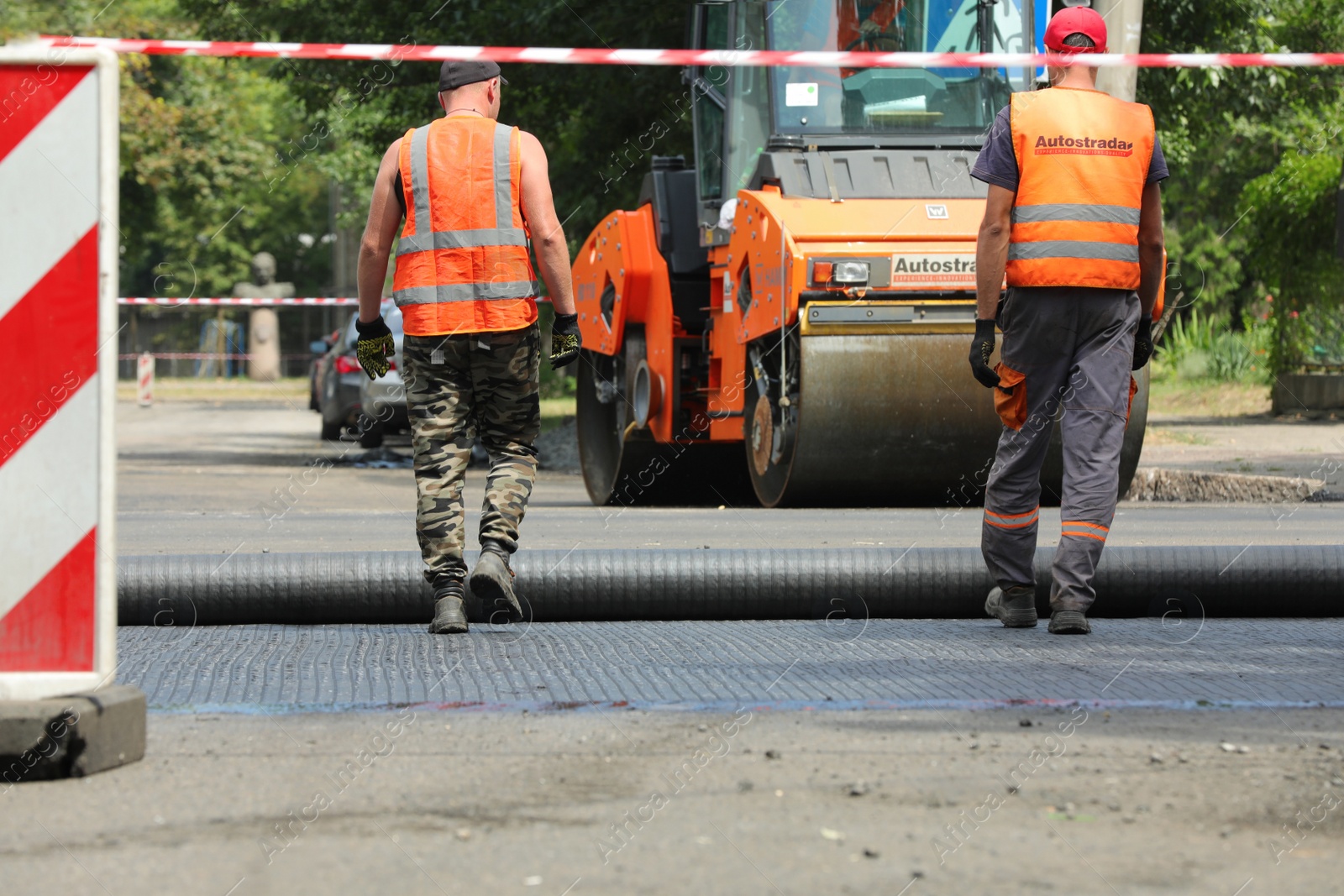 Photo of MYKOLAIV, UKRAINE - AUGUST 04, 2021: Workers with road repair machinery laying new asphalt