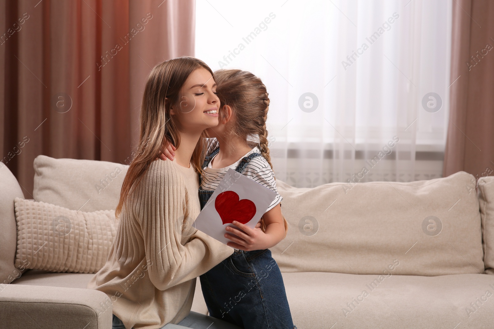 Photo of Little daughter congratulating mom with greeting card at home. Happy Mother's Day