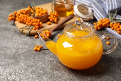 Photo of Delicious sea buckthorn tea and fresh berries on grey table