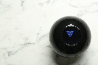 Magic eight ball with prediction Consult Me Later on white marble table, top view. Space for text