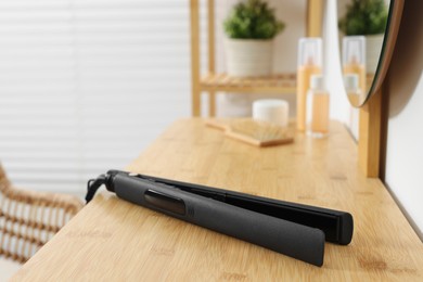 Photo of Black hair iron on wooden table in room