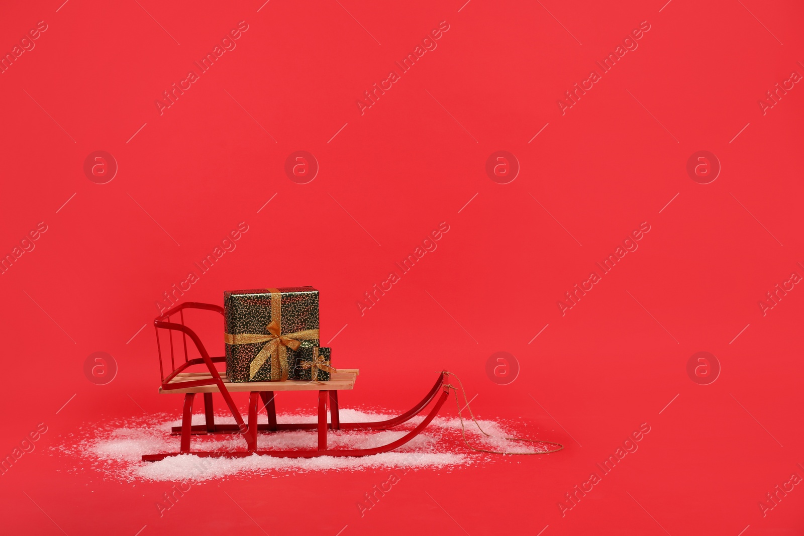 Photo of Sleigh with gift boxes on red background. Space for text