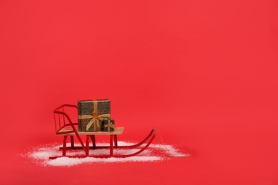 Photo of Sleigh with gift boxes on red background. Space for text