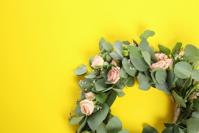 Wreath made of beautiful flowers on yellow background, top view. Space for text