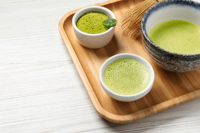 Photo of Fresh matcha tea, bamboo whisk and green powder on white wooden table, closeup. Space for text
