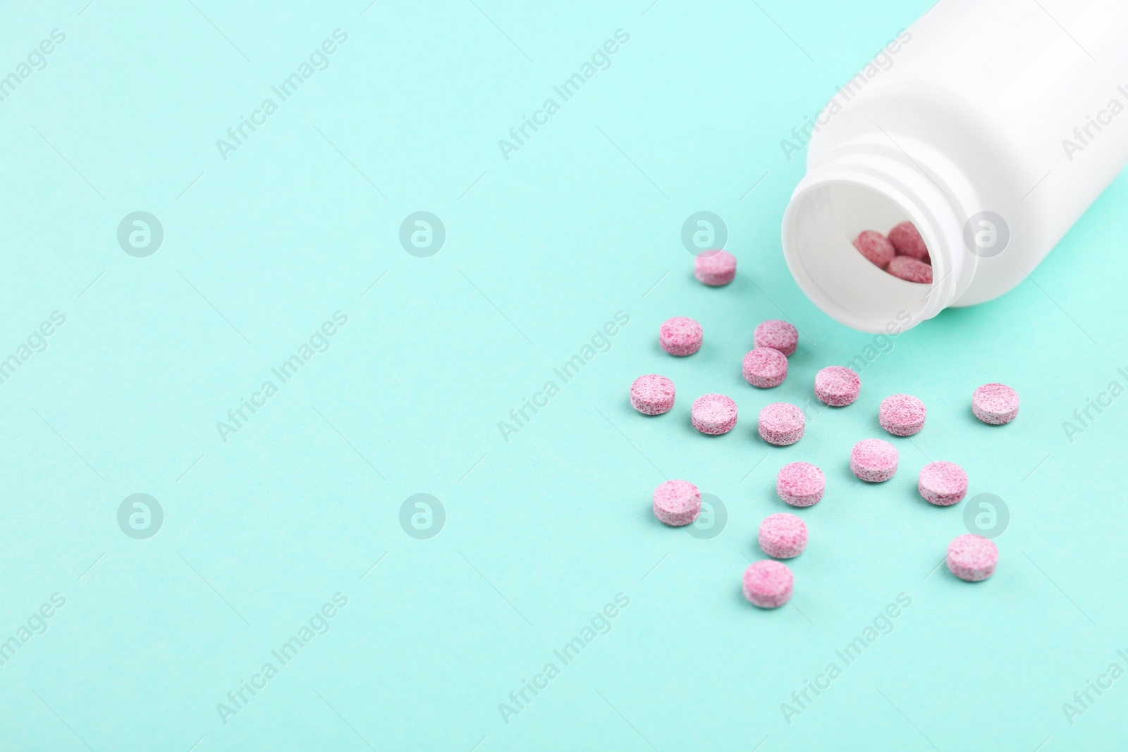 Photo of Bottle and vitamin pills on turquoise background, closeup. Space for text