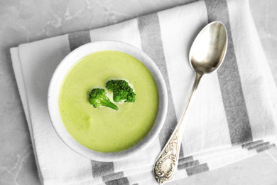 Photo of Delicious broccoli cream soup served on grey marble table, top view